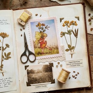 Könnte beinhalten: Eine offene Scrapbook-Seite mit einer Vintage-Illustration einer Fee, einem schwarz-weißen Foto mit der Aufschrift Summer Fields, gepressten gelben Blumen mit der Beschriftung Vogelfuß-Klee, einer Metallschere und zwei Holzspulen mit gelbem Seidengarn.