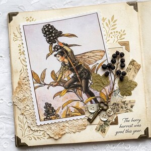 Könnte beinhalten: Eine Vintage-Scrapbook-Seite mit einer Feenillustration, die Beeren trägt. Die Seite enthält getrocknete Blätter, einen dekorativen Schlüssel, Knöpfe und den Text "The berry harvest was good this year."