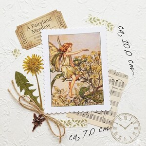 Pode incluir: Uma colagem com uma ilustração de fada vintage, um bilhete que diz "A Fairyland Meadow", flores secas, partituras e um relógio. A ilustração da fada tem aproximadamente 10,0 cm de altura e 7,0 cm de largura.