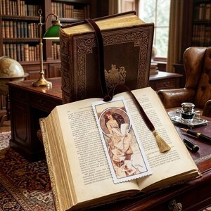 May include: An open antique book with a decorative bookmark featuring an illustration of a woman. The book is on a dark wooden desk, with a larger book behind it. A green desk lamp and a globe are also visible.