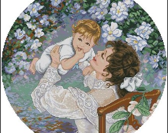 May include: A woman in a white dress holds a baby in her arms. The baby is wearing a white shirt and has a light brown hair. The woman is smiling and looking at the baby. The background is a blurry image of white flowers.
