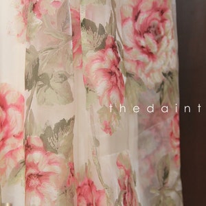 May include: White sheer fabric with a pink and green floral print. The fabric has a delicate, flowing texture. The text "the daintyard" is visible in the lower right corner of the image.
