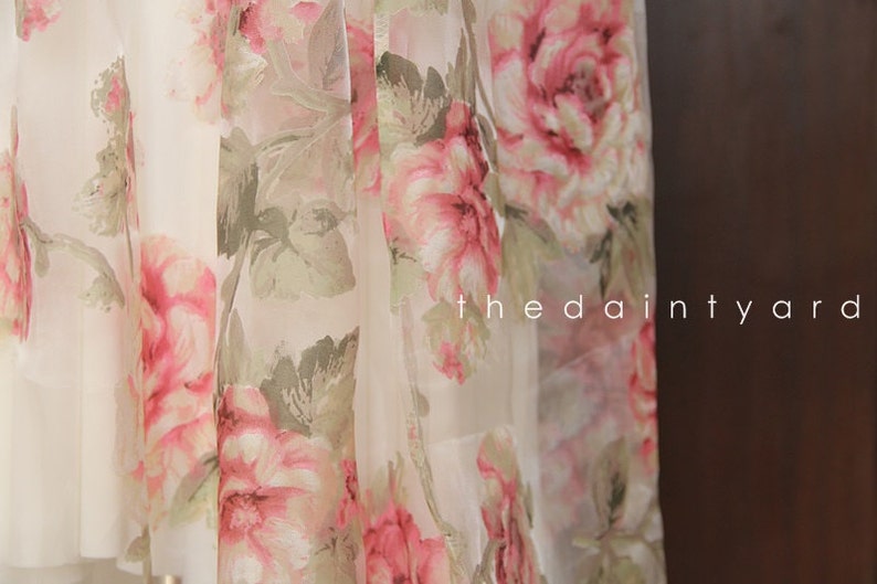 May include: White sheer fabric with a pink and green floral print. The fabric has a delicate, flowing texture. The text "the daintyard" is visible in the lower right corner of the image.