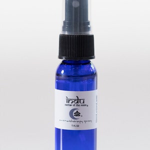 May include: A blue glass bottle with a black spray top and a white label that reads "indu nectar of the moon aromatherapy spray 1 fl oz".