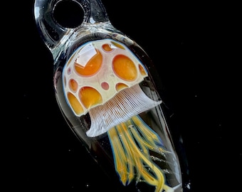 May include: A glass pendant featuring a mushroom with orange and white accents and a yellow and blue stem.