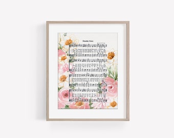 May include: A framed print of the hymn "Amazing Grace" with watercolor floral illustrations in shades of pink, white, and yellow. The lyrics and sheet music are printed in black on a white background.