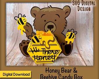 Può includere: Un orso bruno che tiene una scatola di caramelle a forma di alveare gialla e nera con il testo "Hi There Honey". La scatola è decorata con un motivo a nido d'ape e ha tre api.