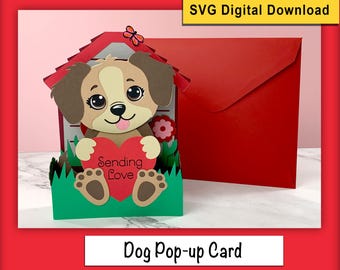 Può includere: Un biglietto pop-up con un cane marrone e bianco che tiene un cuore rosso con il testo "Sending Love". Il cane è in piedi in un'area verde erbosa di fronte a una cuccia per cani rossa. Il biglietto è perfetto per San Valentino o qualsiasi occasione per dimostrare il tuo amore.