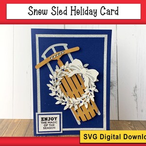May include: A blue card with a white border and a silver glitter border. The card features a brown wooden sled with a white wreath and a white bow. The text "Enjoy the magic of the season" is on a white rectangle at the bottom of the card. SVG Digital Download.