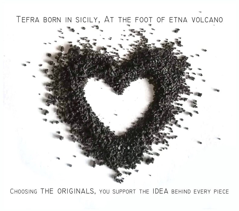 May include: A heart shape made of black volcanic rock from Mount Etna in Sicily. The text "TEFRA BORN IN SICILY, AT THE FOOT OF ETNA VOLCANO" is at the top of the image. The text "CHOOSING THE ORIGINALS, YOU SUPPORT THE IDEA BEHIND EVERY PIECE" is at the bottom of the image.