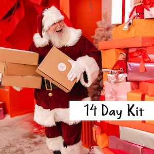 May include: Santa Claus in a red velvet suit with white fur trim holds several brown cardboard boxes. Two small elf dolls sit on a stack of colorful wrapped gift boxes. The text 14 Day Kit is displayed in black on a white rectangular background.