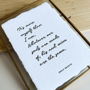 May include: A white framed print with a black handwritten quote by Emily Bront&euml; that reads: "He's more myself than I am. Whatever our souls are made of, his and mine are the same."