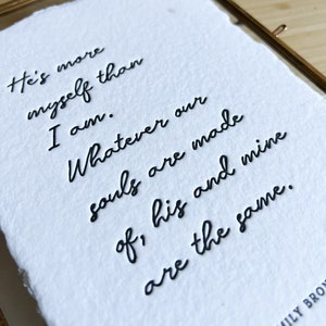 May include: A white paper print with black ink calligraphy that reads "He's more myself than I am. Whatever our souls are made of, his and mine are the same." The text is signed "EMILY BRON".
