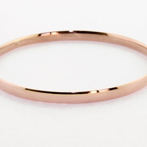 May include: A simple, polished rose gold bangle bracelet.