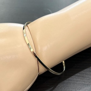 May include: A thin gold bangle bracelet. The bracelet is simple and elegant.