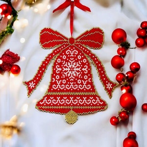 May include: A red and white beaded Christmas bell ornament with a gold bow and a snowflake design. The bell is hanging from a red ribbon.