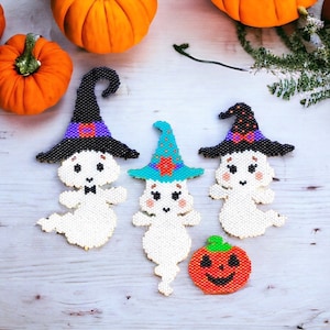 May include: Three white ghost ornaments with different coloured witch hats. The ghosts are made of white beads and have black eyes and a black bow tie. The hats are black with purple, blue, and red accents. There is also a small orange pumpkin ornament with a black smiling face.