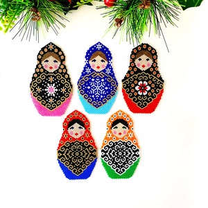 May include: Five colorful beaded Russian nesting doll ornaments with intricate designs. The dolls are arranged in a circle on a white background.