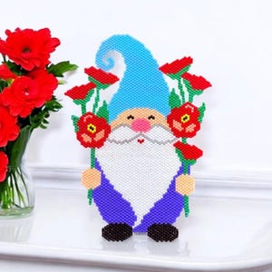 May include: A beaded gnome figurine with a blue hat and purple clothing, holding red flowers with green stems.