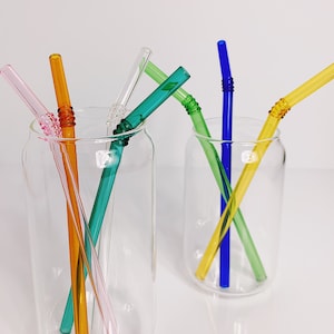 Puede incluir: Seis pajitas para beber de vidrio de colores en dos tarros de vidrio transparentes. Las pajitas son rosa, naranja, amarilla, verde, azul y turquesa.