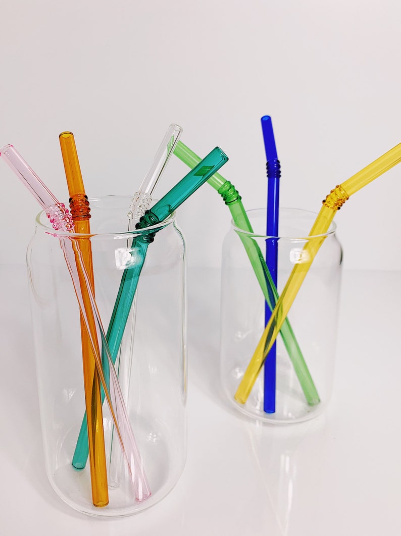 Puede incluir: Seis pajitas para beber de vidrio de colores en dos tarros de vidrio transparentes. Las pajitas son rosa, naranja, amarilla, verde, azul y turquesa.