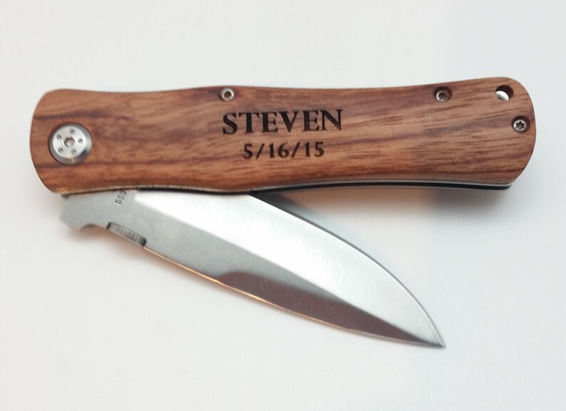May include: A brown wooden pocket knife with a silver blade. The handle is engraved with the name "STEVEN" and the date "5/16/15".