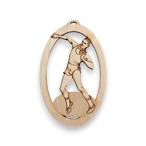 May include: A wooden ornament featuring a silhouette of an athlete throwing a shot put. The ornament is oval shaped and has a hole at the top for hanging.