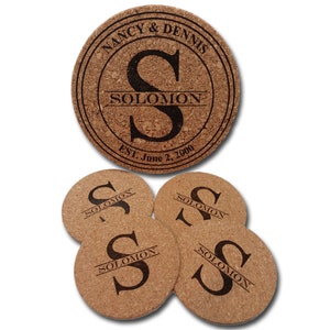 May include: Set of five cork coasters with a personalized design. The large coaster features the names "Nancy & Dennis" and the initial "S" for Solomon, with the text "Solomon" and "Est. June 2, 2000". The four smaller coasters feature the initial "S" and the name "Solomon".