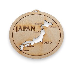 May include: Wooden ornament shaped like the islands of Japan, with the names of the main islands and cities labeled. The ornament is brown and has a hole at the top for hanging.