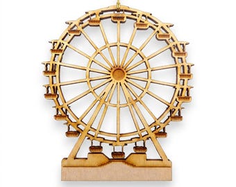 May include: A laser-cut wooden ornament shaped like a Ferris wheel with a circular frame, radiating spokes, and small hanging passenger cars. The natural light brown wood features a smooth finish and is suspended by a thin gold string at the top.