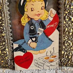 Vintage Litho Mechanical 1940s Little Cow Girl Segurando Espátula Grelhar Cozinhar "Vamos nos Reunir" Cartão de Dia dos Namorados
