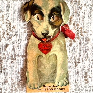 Könnte beinhalten: Vintage Valentinstagskarte mit einem Cartoon-Hund mit großen Augen und einem roten Herzen, auf dem "To my Valentine" steht. Die Karte trägt außerdem den Text "Remember me my Sweetheart".