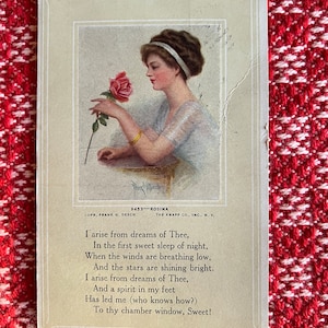 May include: A vintage postcard featuring a woman in a white dress holding a red rose. The text on the postcard reads: "I arise from dreams of Thee, In the first sweet sleep of night, When the winds are breathing low, And the stars are shining bright. I arise from dreams of Thee, And a spirit in my feet Has led me (who knows how?) To thy chamber window, Sweet!"