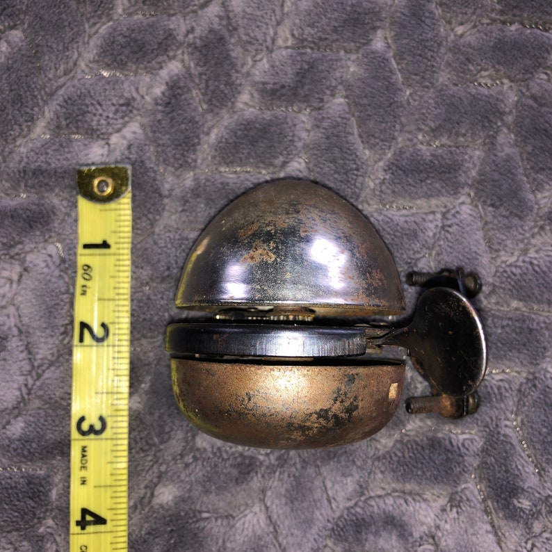 May include: A vintage silver bicycle bell with a chrome finish and a brass bell. The bell is in good condition with some signs of wear and tear.