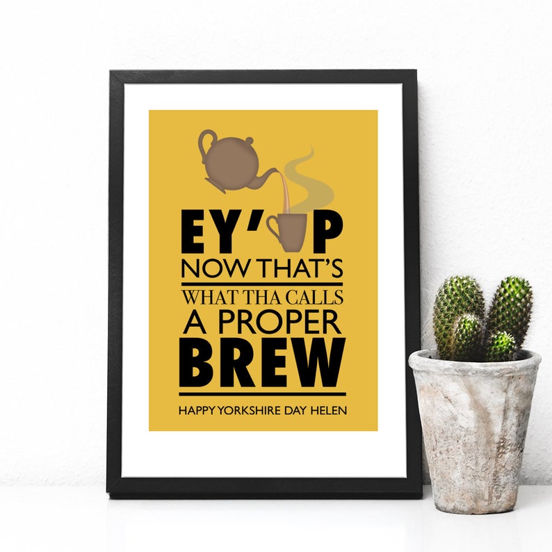 May include: A yellow poster with black text that reads "Ey' up now that's what tha calls a proper brew. Happy Yorkshire Day Helen."  A brown teapot pours tea into a brown cup.