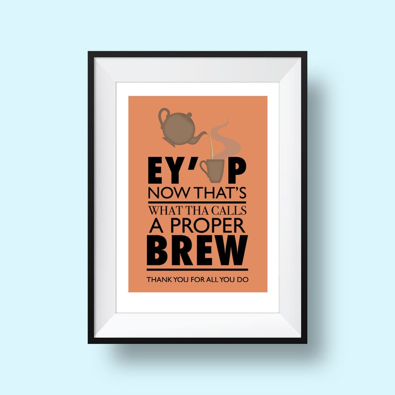 May include: A framed print with an orange background and a black teapot pouring tea into a cup. The text reads "Ey'up Now That's What Tha Calls A Proper Brew" and "Thank You For All You Do".