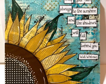 May include: Square artwork featuring a large sunflower with yellow petals and a brown center. The background is a textured turquoise with text that reads "Keep your face always to the sunshine and the shadows will fall behind you - Walt Whitman."