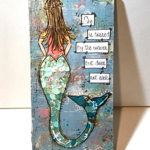 May include: A blue and green mermaid with a pink top and a crown of flowers. The background is a light blue with white and pink accents. The text reads "She is tossed by the waves but does not sink."