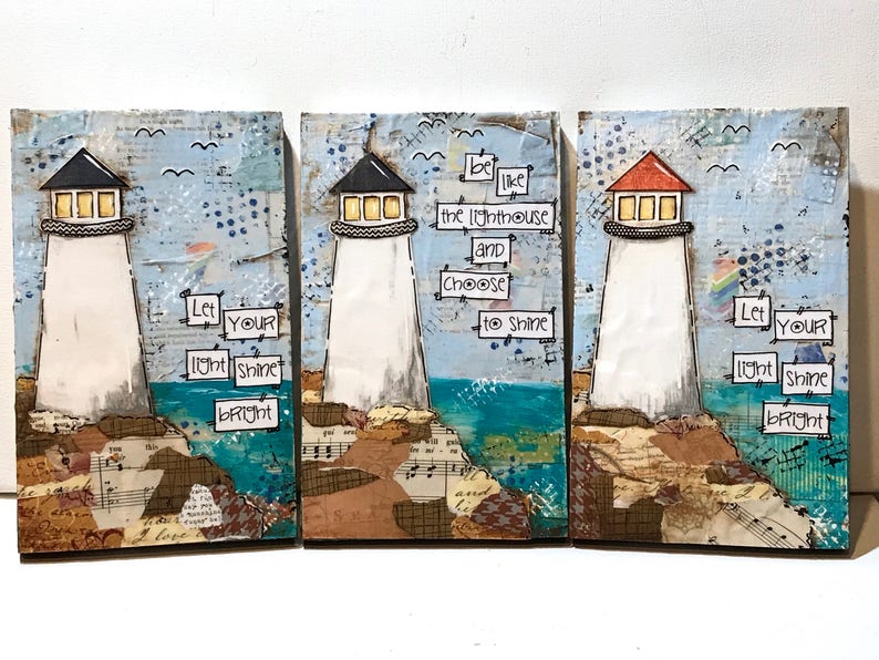 May include: A set of three rectangular wall art panels featuring mixed media collages of lighthouses on rocky shores. The panels include text that reads: Let your light shine bright and be like the lighthouse and choose to shine.