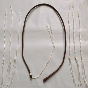 May include: A collection of white and brown cords and ropes. The image features several white cords with knotted ends and a brown, looped cord. The cords are arranged against a white background.