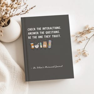 May include: A dark gray journal with white text that reads: CHECK THE INTERACTIONS. ANSWER THE QUESTIONS. BE THE ONE THEY TRUST. Below the text are cartoon illustrations of a pill bottle, mortar and pestle, capsule, bag, and pill organizer.