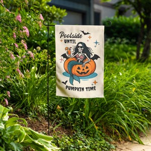 Może przedstawiać: Beżowa flaga ogrodowa z motywem Halloween. Przedstawia szkielet syreny siedzącej w dyni, z napisem "Poolside until Pumpkin Time". Flaga jest wystawiona na zewnątrz w ogrodzie.