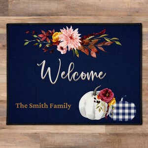 May include: A navy blue welcome mat with a white pumpkin, a floral arrangement, and the text "Welcome The Smith Family".