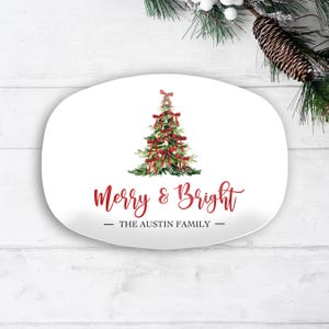 May include: White oval serving platter with a watercolor Christmas tree design. The tree is decorated with red bows. The words "Merry & Bright" are written in red script, with "The Austin Family" below.