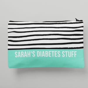 May include: A black and white striped zippered pouch with the text "SARAH'S DIABETES STUFF" on a teal green background.