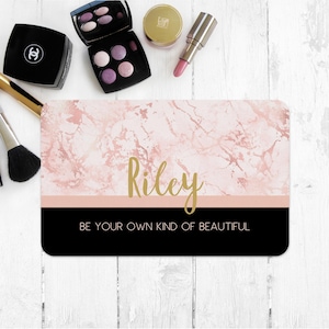 May include: A pink and gold marble design makeup bag with the name "Riley" and the text "Be your own kind of beautiful".