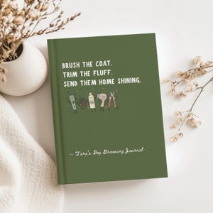 May include: A dark olive green journal featuring the white text BRUSH THE COAT. TRIM THE FLUFF. SEND THEM HOME SHINING. Below the text are small cartoon illustrations of grooming tools, and at the bottom is the text Tara's Dog Grooming Journal.
