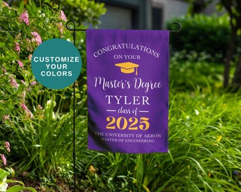 May include: A purple graduation garden flag with gold text that reads "Congratulations on your Master's Degree" and the graduate's name, class year, and university. A teal circle says "Customize Your Colors".