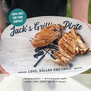 May include: An oval-shaped grilling plate with grilled chicken. The plate has a wood-grain design and text that reads "Jack's Grilling Plate" and "Grill Master". The plate is dishwasher, microwave, and oven safe.