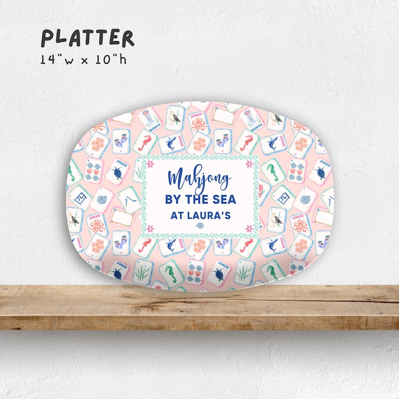 May include: Oval platter with a pink background and a pattern of Mahjong tiles. The platter is 14 inches wide and 10 inches high. The text "Mahjong by the Sea at Laura's" is in the center.